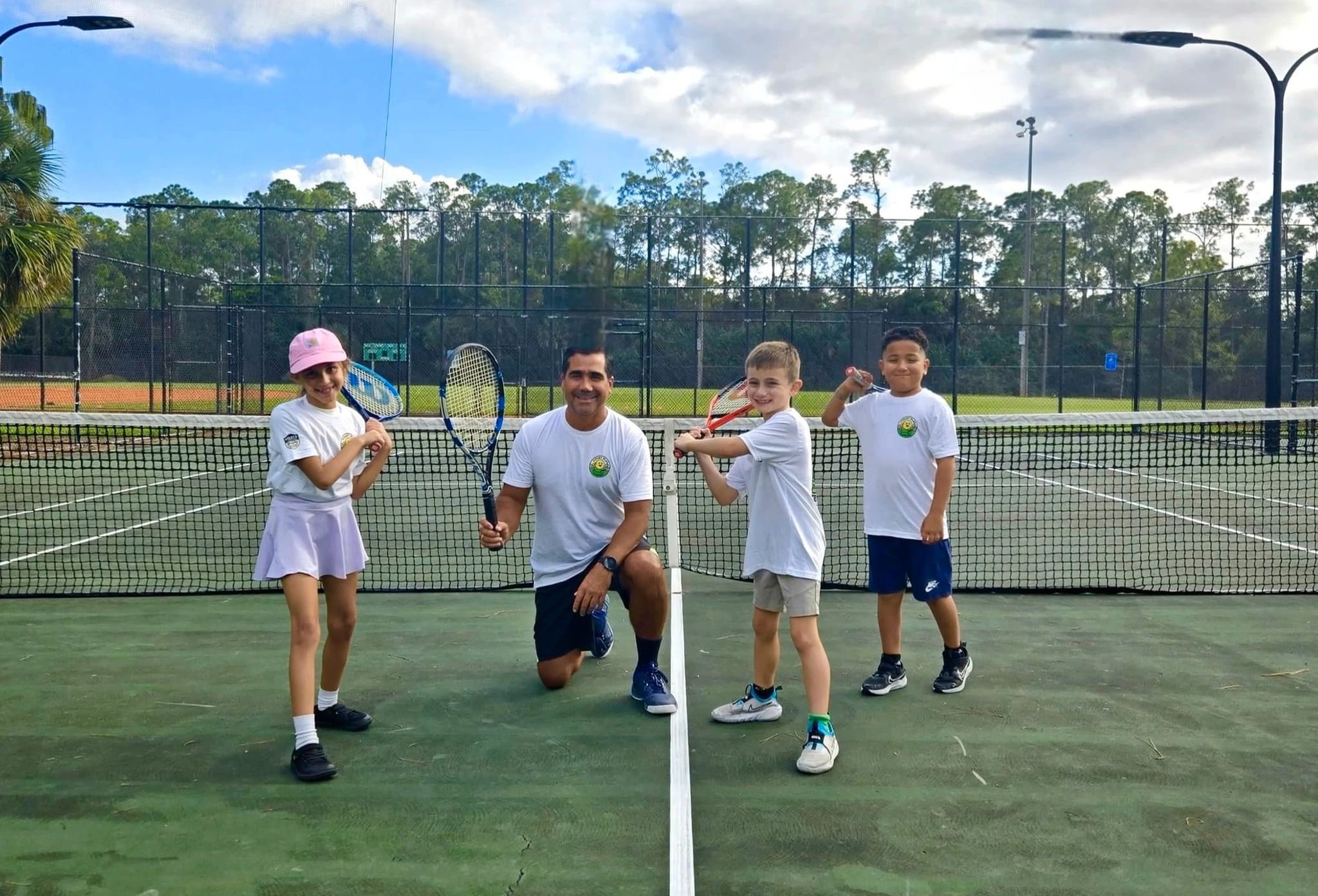 Tennis instructor with young students on outdoor court